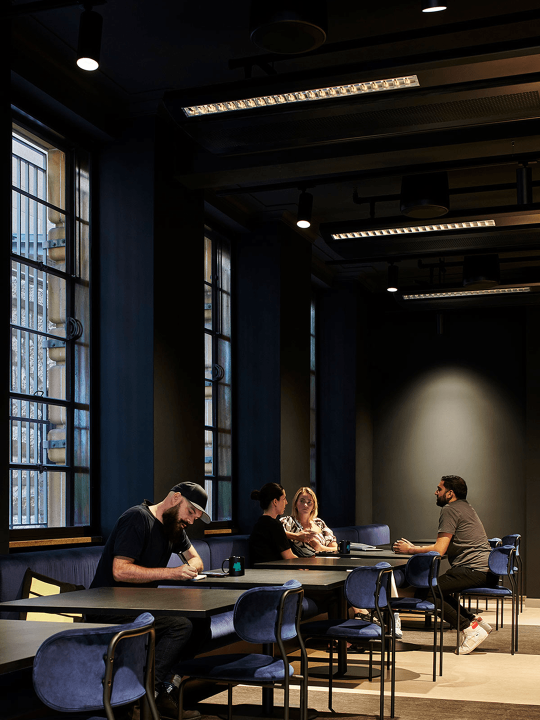 M+C Saatchi employees working in a lofted office space with dramatic lighting.
